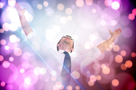 Handsome businessman cheering with arms up against light glowing dots on purpleの写真素材