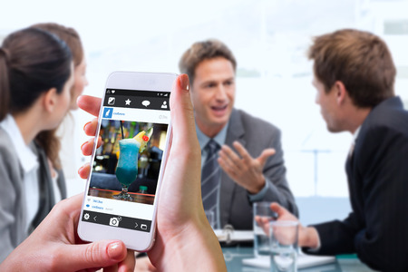 Hand holding smartphone against close up on mouth watering cocktailsの写真素材