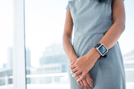 Businesswoman wearing a smartwatch with arms folded in the officeの写真素材