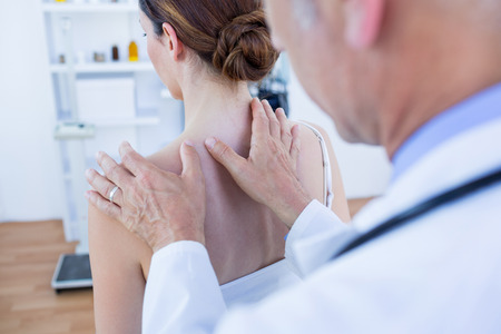 Doctor doing shoulder massage to his patient in medical officeの写真素材