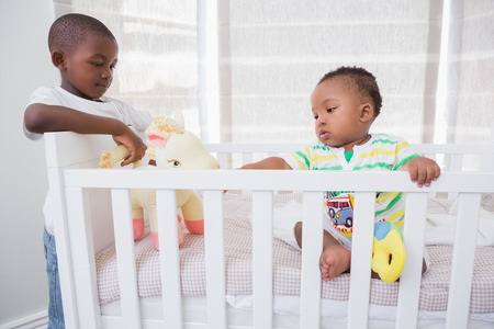 Babyboy playing with his brother in his bed at home in bedroomの写真素材