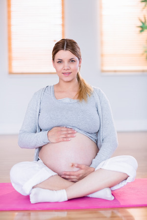 Pregnant woman holding her bump at homeの写真素材