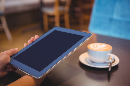 Close-up of digital tablet and coffee on table in the coffee shopの写真素材