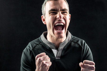 Excited rugby player yelling out on a black background