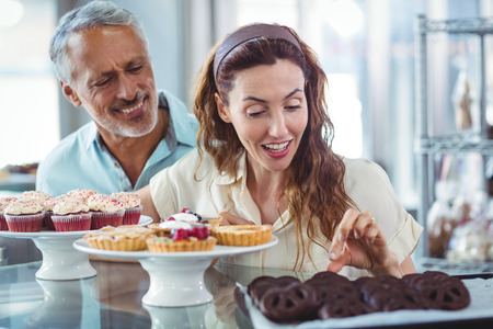Cute couple choosing chocolate cakes in the bakery storeの写真素材