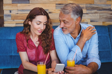 Cute couple sitting in cafe drinking orange juiceの写真素材