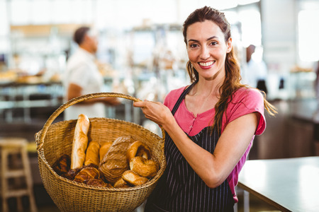Pretty waitress carrying basket of bread at the bakery
