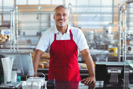 Barista smiling at camera behind counter in the bakeryの写真素材
