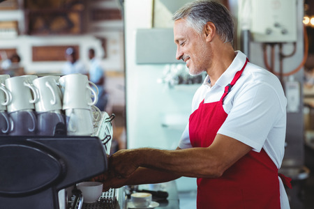 Happy barista using the coffee machine at the cafeの写真素材