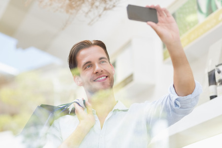 A happy smiling man taking a selfies at the mallの写真素材