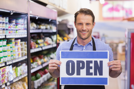 Portrait of a smiling handsome holding a sign in supermarket