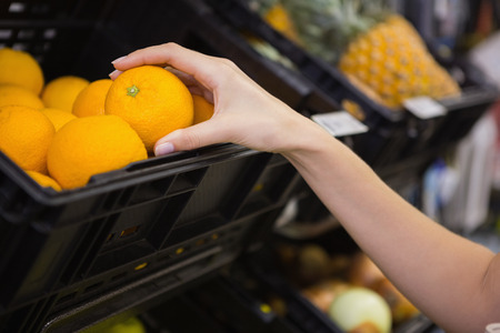 Smiling pretty blonde woman buying oranges at supermarketの写真素材