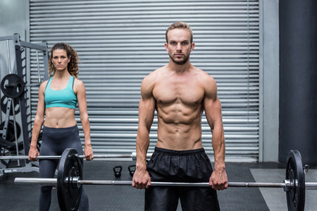 Portrait of a muscular couple lifting weight togetherの写真素材