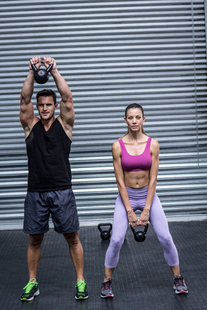 Muscular couple lifting kettlebells at the crossfit gymの写真素材