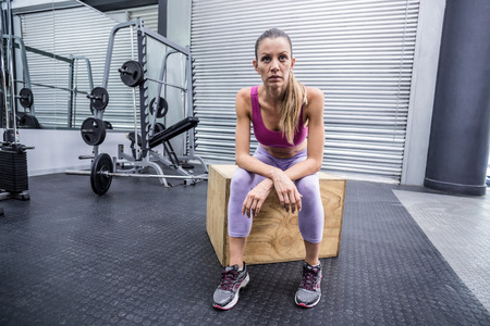 Muscular woman sitting on a wooden box with arms crossed