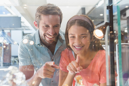 Young happy couple looking at jewellery from behind a window of a jewellery storeの写真素材