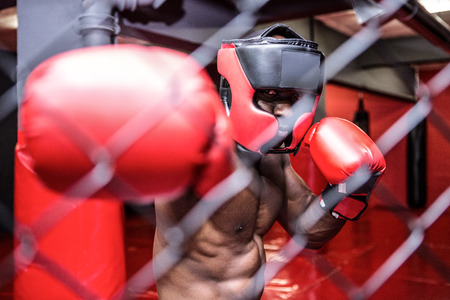 Young bodybuilder with helmet standing behind an iron fence in the crossfit gym