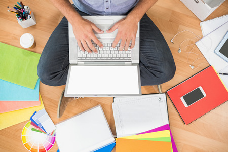 Upward view of a young creative businessman working on laptopの写真素材