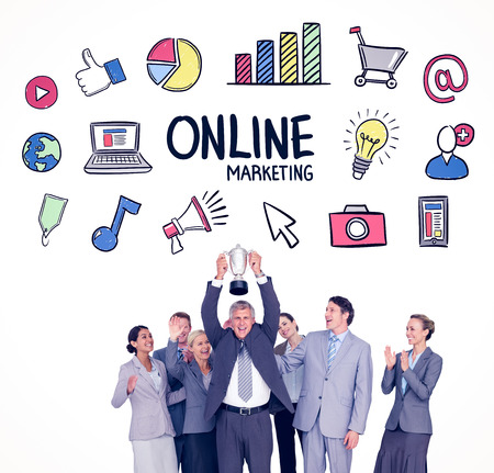 Excited business team cheering at camera with trophy against online marketingの写真素材