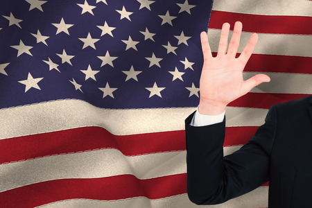 Businessman in suit with hand raised against united states of america flagの写真素材