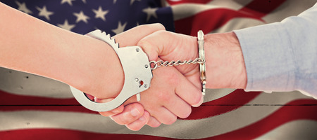 Handcuffed business people shaking hands against white woodの写真素材
