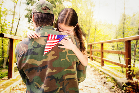 Father reunited with daughter against bridge with railings leading towards forestの写真素材