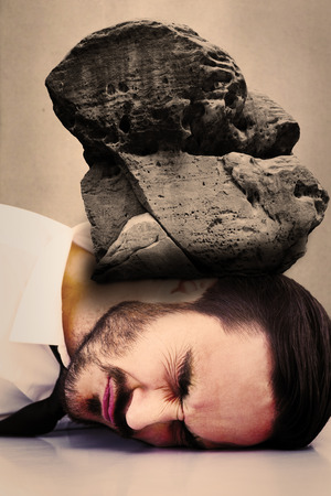 Businessman banging his head against grey roomの写真素材