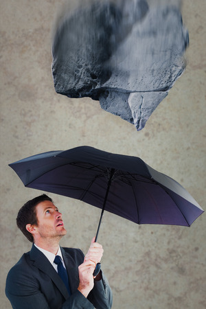 Businessman sheltering under black umbrella against grey roomの写真素材