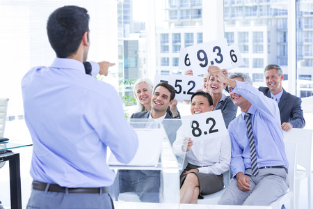 Smiling business team showing paper with rating in the officeの写真素材