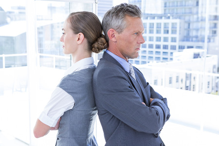 Two angry business colleagues standing back to back in the officeの写真素材