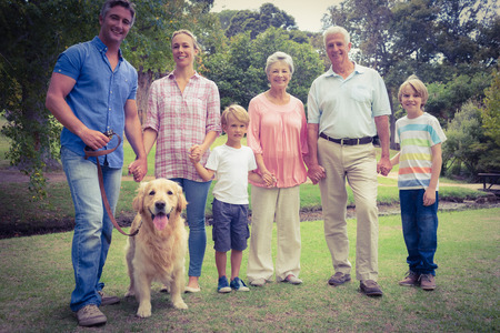 Happy family smiling at the camera with their dog on a sunny dayの写真素材