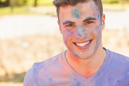 Young man having fun with powder paint on a sunny dayの写真素材