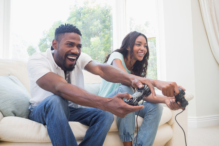Happy couple on the couch playing video games at home in the living room