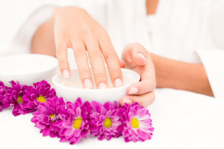 Close-up of hand in bowl along flowers and candleの写真素材