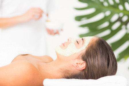 Side view of an attractive woman having white cream on her face at spa centerの写真素材