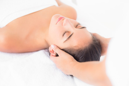 Close up of an attractive young woman receiving head massage at spa centerの写真素材