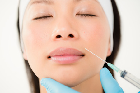 Woman receiving botox injection on her lips in medical officeの写真素材