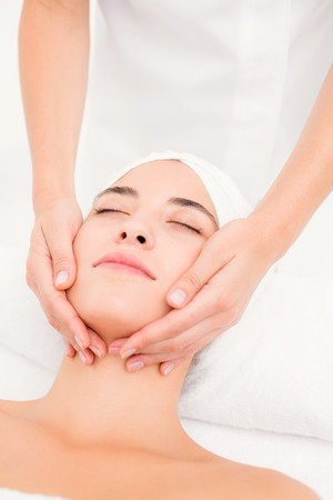 Close up of an attractive young woman receiving facial massage at spa centerの写真素材
