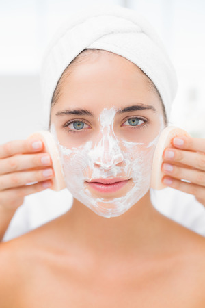 Upward view of hands cleaning woman face with sponge at spa centerの写真素材