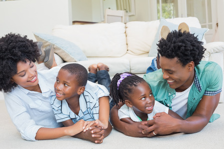 Happy family lying on the floor at home in the living roomの写真素材