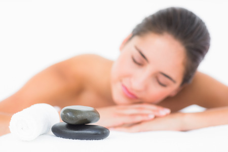 Smiling pretty brunette on massage table with white backgroundの写真素材