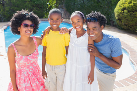 Happy family smiling at camera in the garden at homeの写真素材