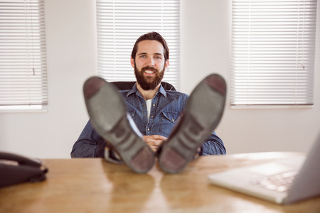 Hipster businessman relaxing at his desk in his officeの写真素材