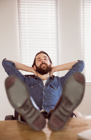 Hipster businessman relaxing at his desk in his officeの写真素材