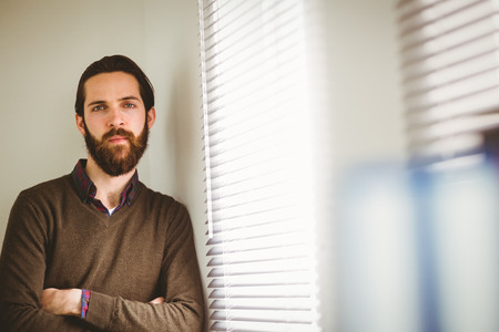 Hipster businessman leaning beside window in his officeの写真素材