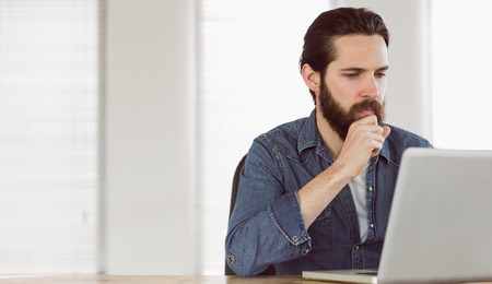 Hipster businessman working on his laptop in his officeの写真素材