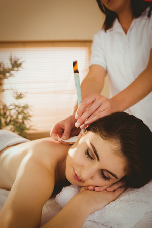 Young woman getting ear candling treatment in therapy roomの写真素材