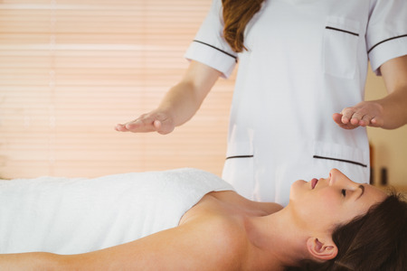 Young woman having a reiki treatment in therapy roomの写真素材