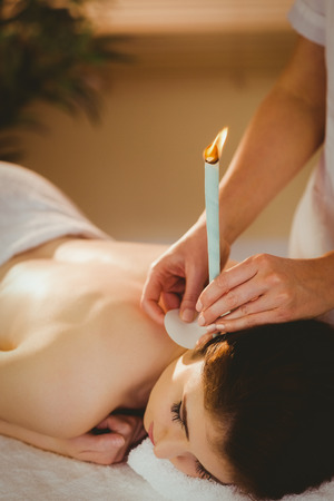 Young woman getting ear candling treatment in therapy roomの写真素材