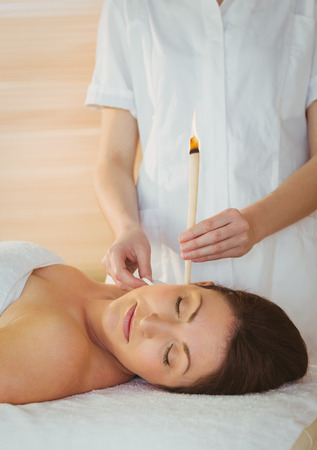 Young woman getting an ear candling treatment in therapy roomの写真素材